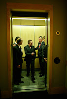a group of men in suits standing in an elevator