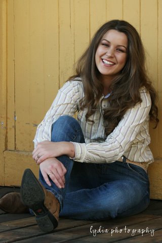 Senior laughing with one knee up sitting on the floor at lifestyle senior portraits in Colfax, California