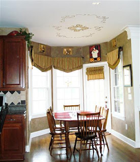 Breakfast room with gorgeous view to rear yard features artistic stenciling on the ceiling above the table area and decorator window dressings