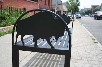 Black iron buffalo in an arch on the side of a bus bench