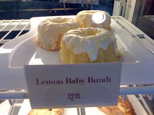 Yellow mini-cakes in a case with a sign in front that reads Lemon Baby Bundt