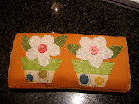 Bolsa de tela plegada decorada con dos macetas en flor en tela.