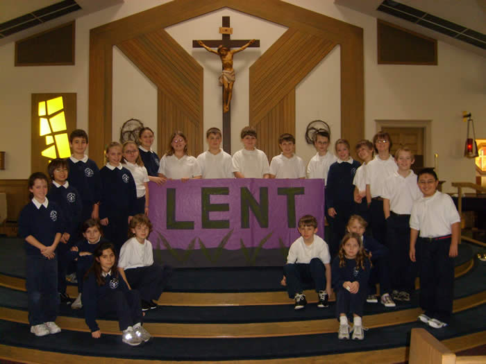 Children from the 4-6 Campus gather with a Lent banner in front of the altar of Blessed Mother Parish
